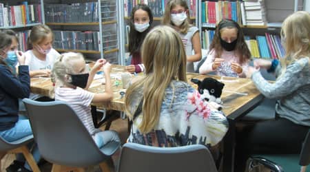 Dzieci wykonujące prace plastyczne przy stole.